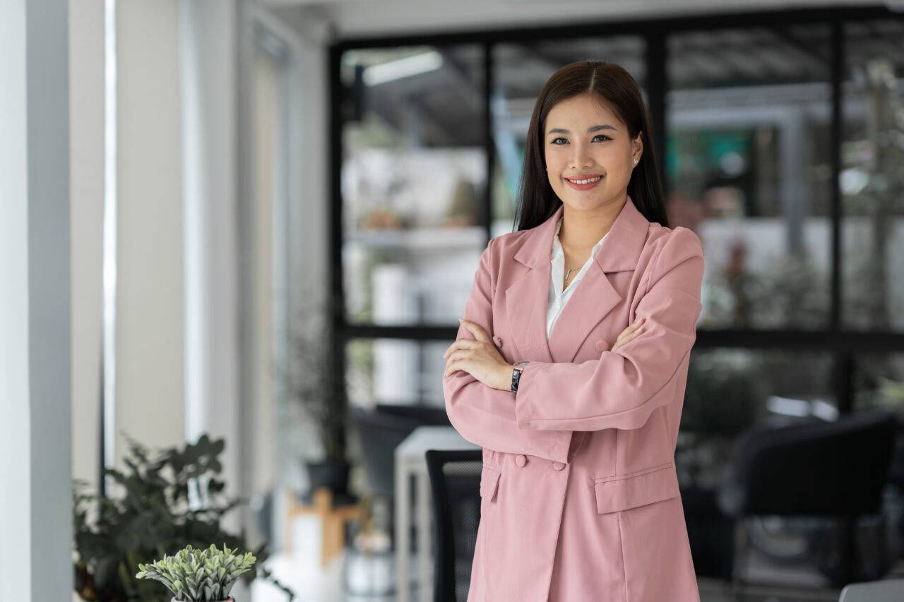 Young Asian businesswoman in casual suit happy smile While in modern office room with laptop about w